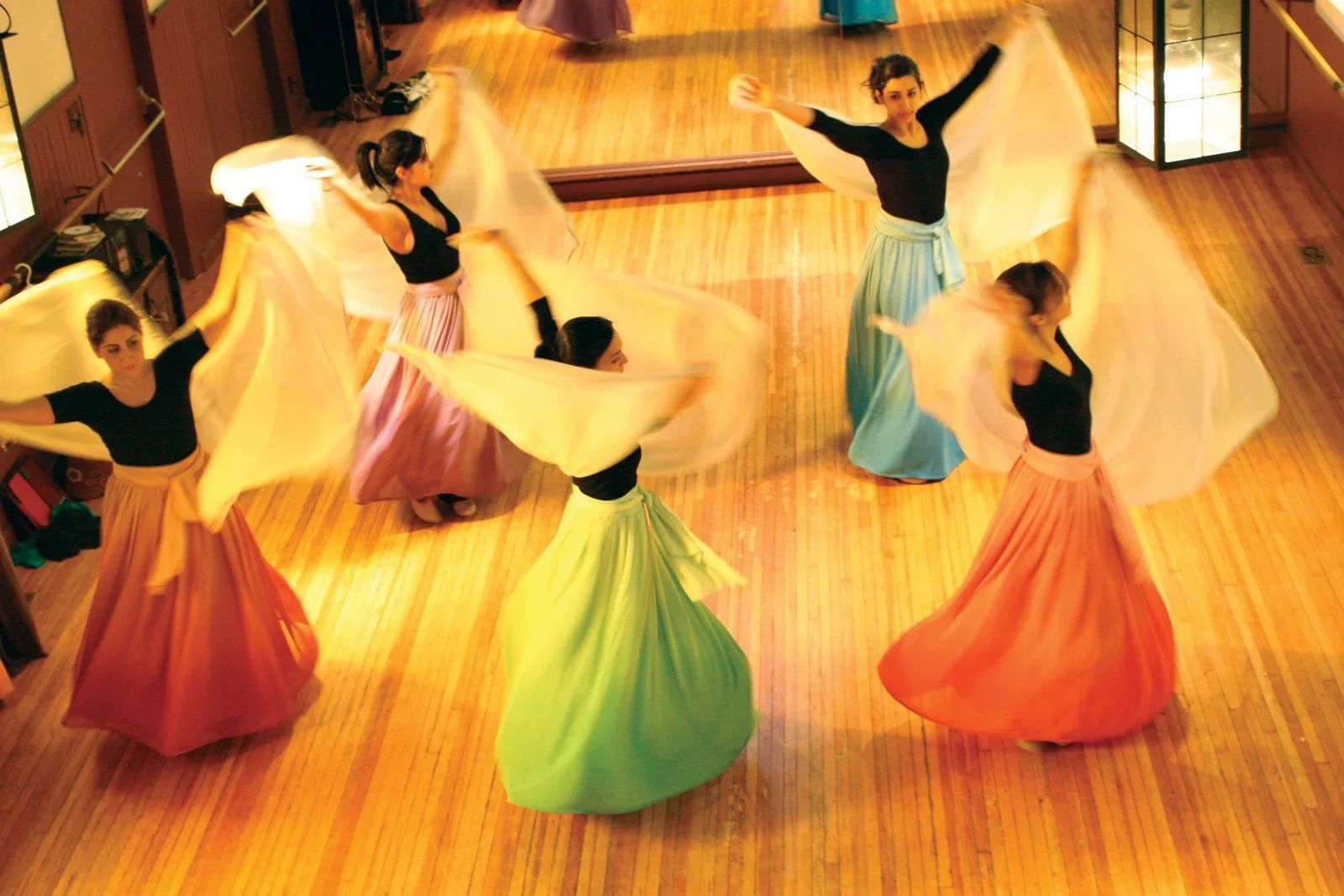 Still from The Neighbor: dancers in brightly coloured skirts on a wooden floor.